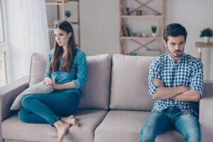 Paar nach Streit auf Sofa – Beziehungsdynamik Dramadreieck und stumme Zeugen