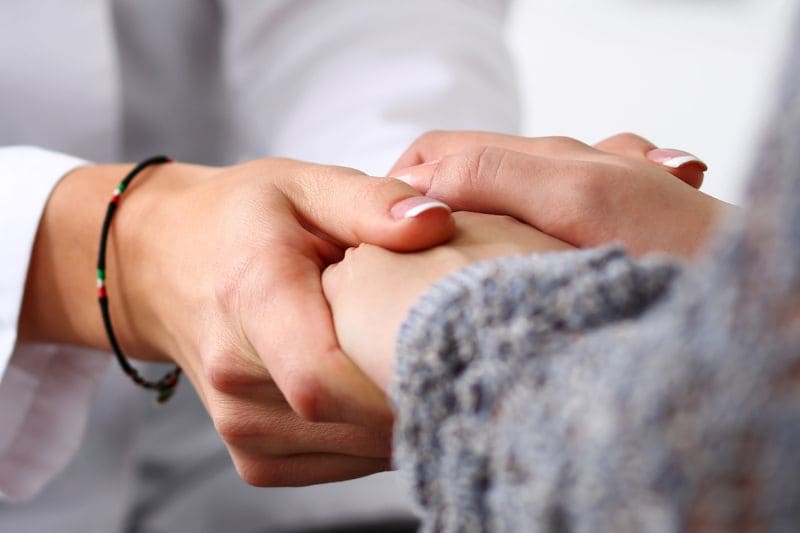 Verwundete Heiler – Ärztin hält Patientin die Hand